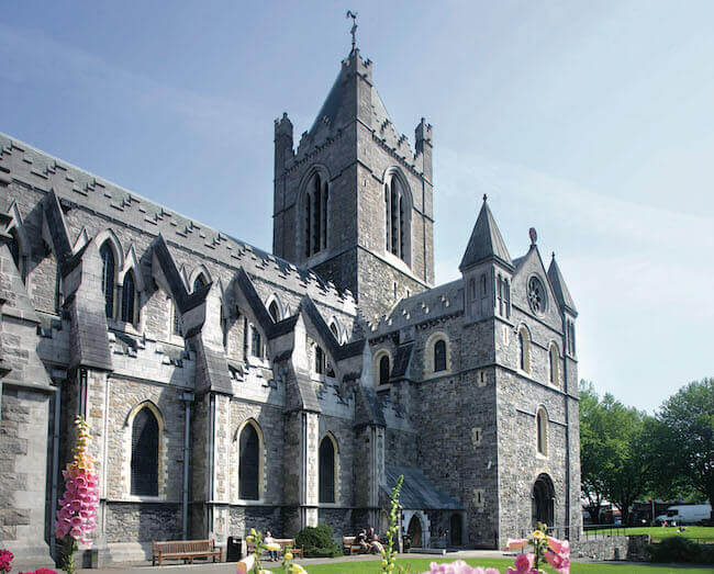 Historic stone cathedral with Gothic architecture and tall spires under a clear blue sky.